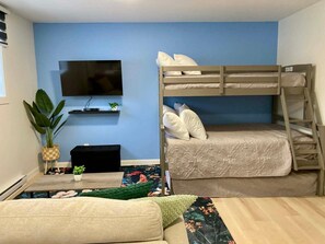 A bunk bed with pillows, a television on the wall, a small plant, and a sofa. - Large, modern and comfortable private room (Rimouski)