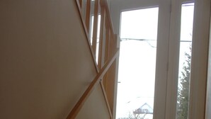 A wooden staircase with a handrail leading to a door.