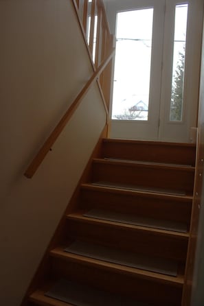 A wooden staircase with a handrail leading to a door.
