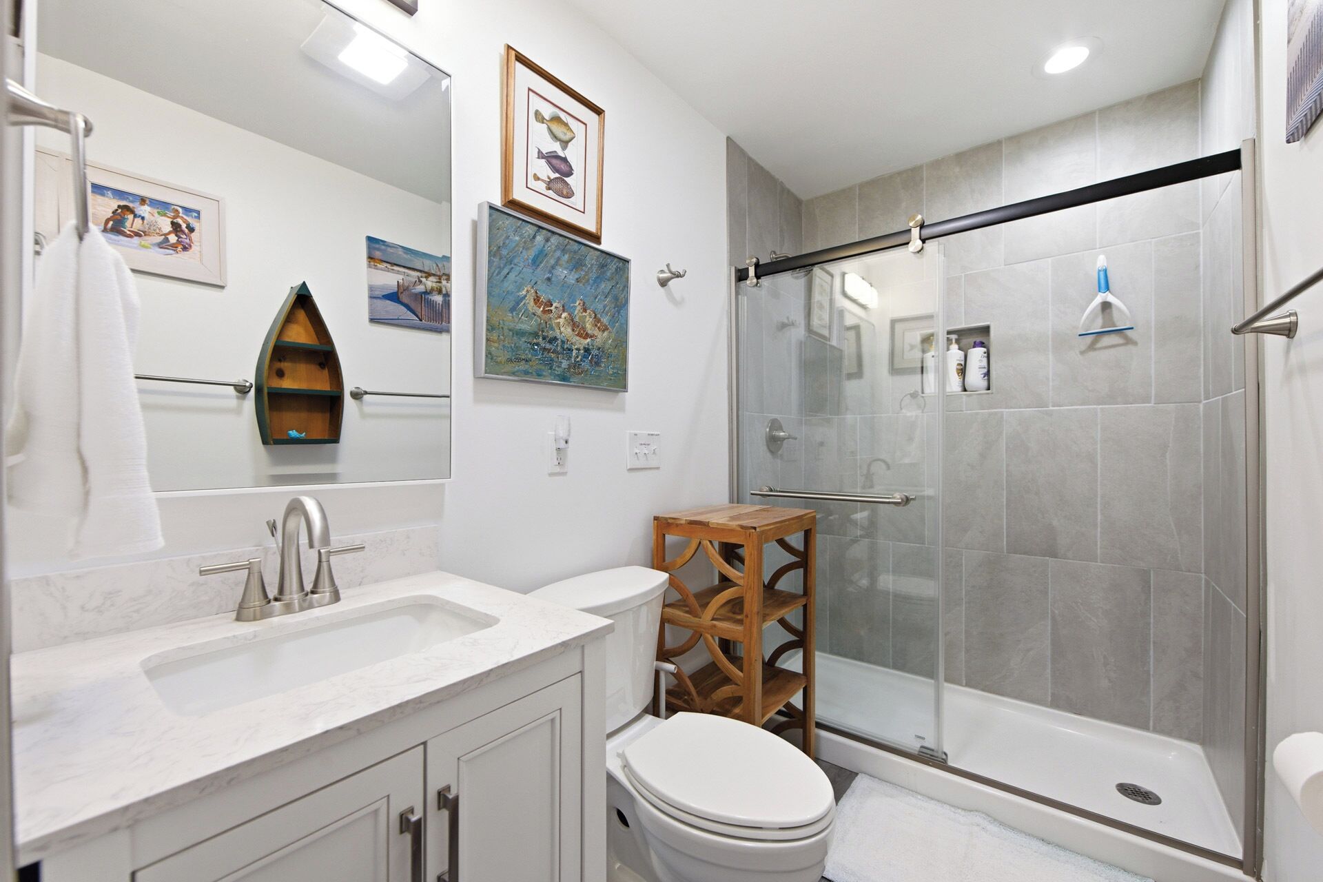 A modern bathroom with a glass-enclosed shower, a wooden vanity, and a toilet.