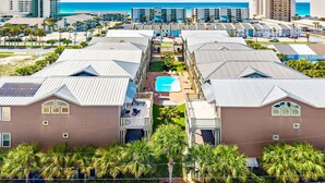 Un complexe hôtelier comprenant plusieurs bâtiments, une piscine centrale et offrant une vue sur la plage.