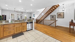 Une cuisine spacieuse avec des meubles de rangement en bois, un lave-vaisselle et un escalier en bois menant à un autre niveau.