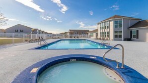 Un área de piscina con un jacuzzi, sillas de descanso y una terraza amurallada.