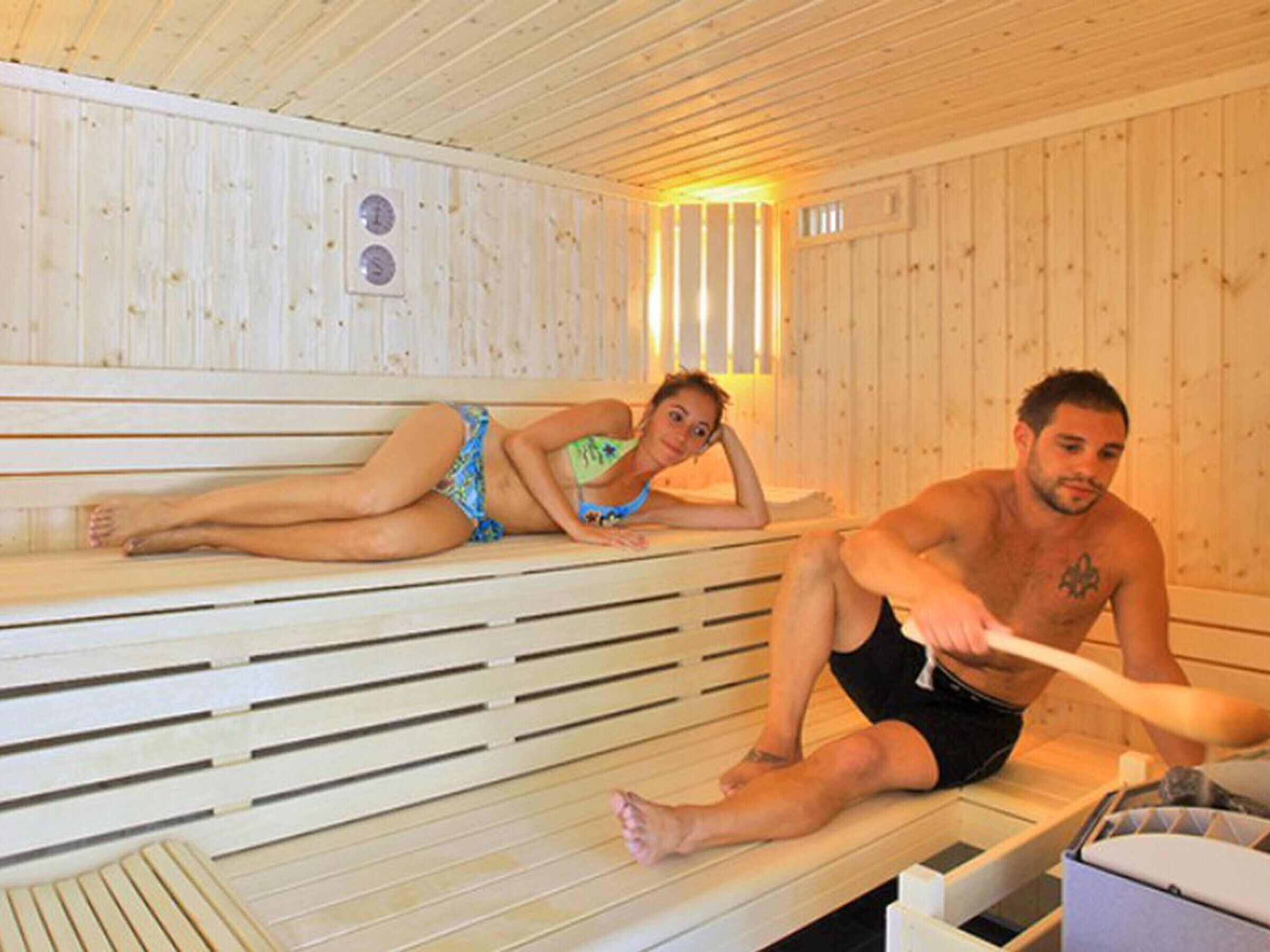 A sauna with wooden benches and a visible thermometer.