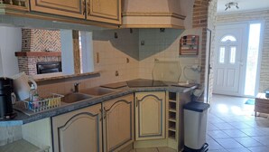 Een keuken met een ingebouwde kookplaat, een dubbele spoelbak en een prullenbak.