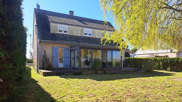 Een huis met twee verdiepingen, een pannendak, een glazen voordeur en een kleine voortuin.