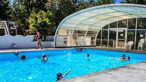 Una piscina con un recinto in vetro, circondata da un solarium in pietra.