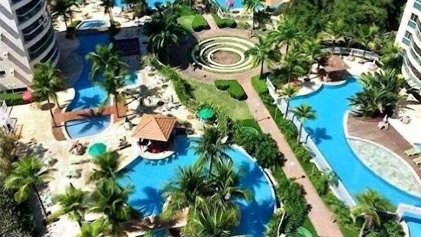 A resort with multiple swimming pools, palm trees, and high-rise buildings. - Excellent apartment in Rio2 - Olympic Barra (Rio de Janeiro)