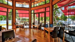 Ein Restaurant mit Holzbalken, großen Fenstern und Außenbereich.