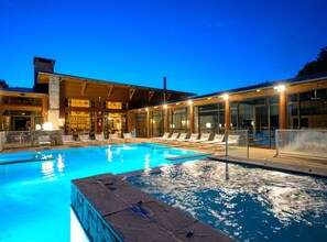 Ein Schwimmbad mit Liegestühlen und einem Gebäude mit großen Fenstern.