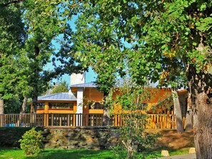 A building with a stone wall, a wooden fence, and a tree in the foreground. - Chalet with terrace - 6 guests (Albi)