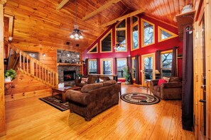 Un salon spacieux doté d’une cheminée, de parquets en bois et d’un plafond haut.