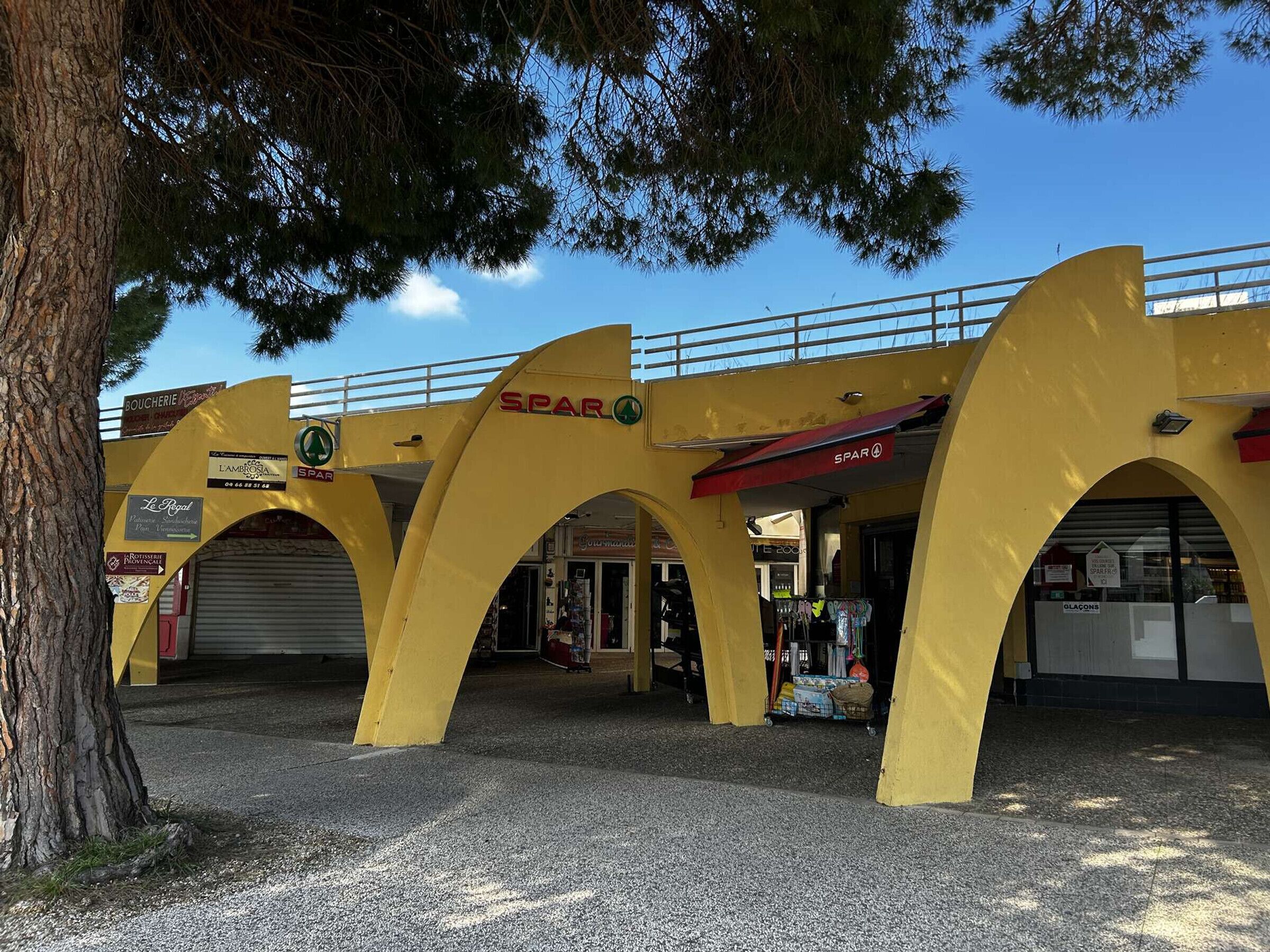Un arco giallo con segnaletica per 'SPAR' e 'BOUCHERIE'.