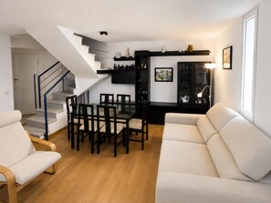 A modern living room with a staircase, a dining area, and a sofa. - Lodging in La Fosca - Palamós (Palamós)