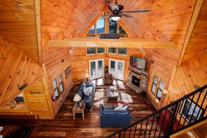 L’intérieur d’une cabane en rondins comprend une chambre à coucher située en mezzanine, un salon avec une cheminée et un coin repas.