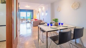 Un comedor moderno con una mesa lista para dos personas, un sofá y vistas al exterior.