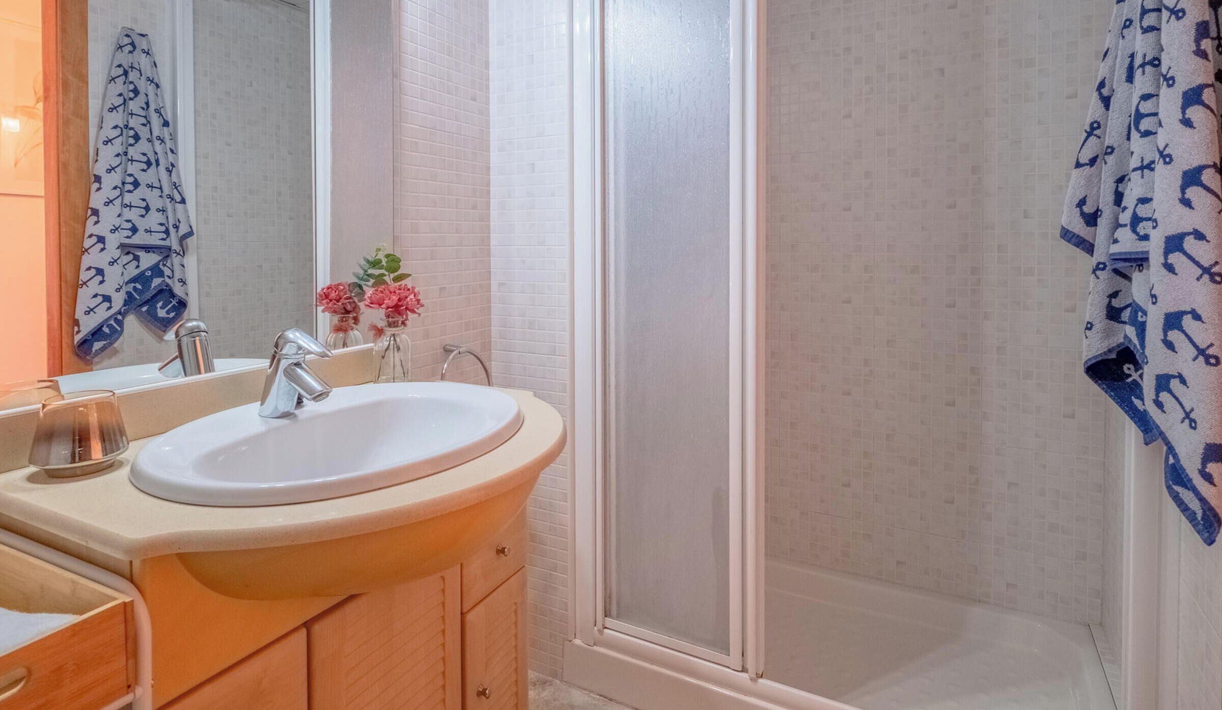 A bathroom with a sink, mirror, and shower.