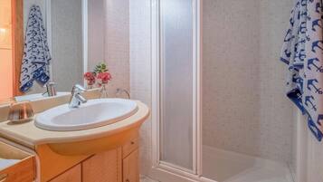 A bathroom with a sink, mirror, and shower.