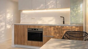A modern kitchen with white cabinets, a built-in oven, and a window with a view.