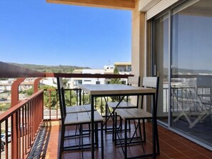 Un balcon avec une table et des chaises, une vue sur la ville et un bâtiment en arrière-plan.