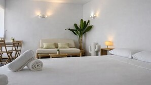 Un dormitorio minimalista con cama, mesita de noche, un cactus y una planta.