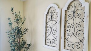 Una habitación con una planta en maceta, un radiador y dos paneles metálicos decorativos en la pared.
