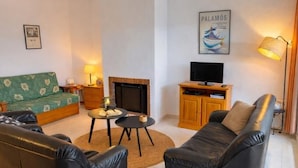 Una sala de estar con chimenea, sofá, mesa de centro, televisor y lámpara.