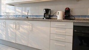 Una cocina moderna con armarios blancos, una encimera y un lavavajillas.