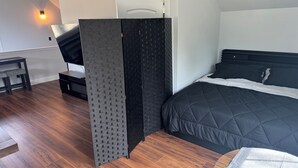 A bedroom with a bed, a desk, and a partition.