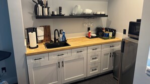 A compact kitchen with a sink, countertop, cabinets, and a microwave.