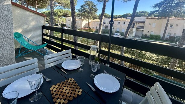 Tavolo apparecchiato per due con vista su edifici e alberi.
