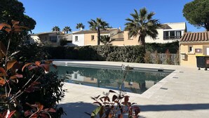Zona residenziale con piscina, palme e case con tetti in tegole.