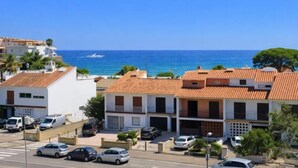 Zona residencial costera con edificios, coches aparcados y una vista despejada del mar.