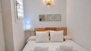 Habitación de hotel con una cama, dos lámparas fijadas a la pared y tres obras de arte enmarcadas.