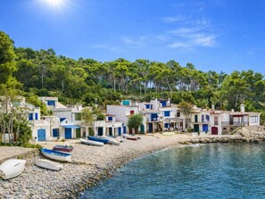 Un village côtier aux bâtiments blancs, avec une plage rocheuse et des bateaux.