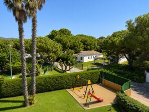 A playground with swings and a slide, surrounded by well-maintained grass and trees. - Apartment with sea view in La Fosca - details coming soon (Palamós)