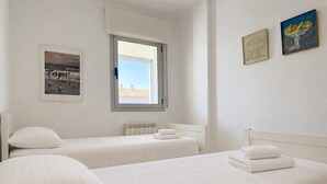 Quarto de hotel com duas camas, uma janela e obras de arte nas paredes.