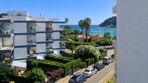 Un edificio de varios pisos con balcones, un estacionamiento y vistas al mar y a los barcos.