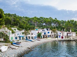 Un village côtier doté de bâtiments traditionnels, d’une plage rocheuse et de bateaux.