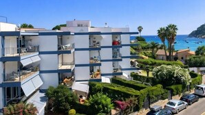 Un edificio moderno de varios pisos con balcones, vistas despejadas al mar y jardines bien cuidados.