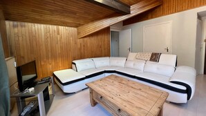 Una sala de estar moderna con un sofá seccional, una mesa de centro de madera y un televisor sobre un mueble bajo.