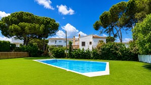 A swimming pool surrounded by well-maintained grass, with a white building and trees in the background. - Comfortable apartment near the beach - 4 guests (Palamós)
