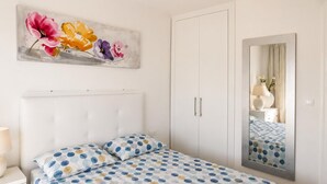 A bedroom with a bed, a nightstand, a dresser, a wardrobe, a mirror, and a floral painting on the wall. - Comfortable apartment near the beach - 4 guests (Palamós)