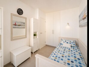 A bedroom with a bed, a bench, a wardrobe, a clock, and a framed picture. - Comfortable apartment near the beach - 4 guests (Palamós)