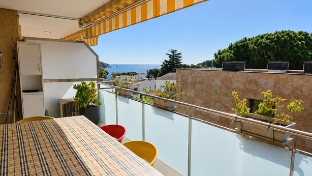 A balcony with a table and chairs, a potted plant, and a view of the sea and buildings. - Comfortable apartment near the beach - 4 guests (Palamós)