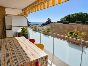 A balcony with a table and chairs, a potted plant, and a view of the sea and buildings. - Comfortable apartment near the beach - 4 guests (Palamós)