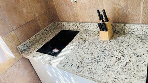 A kitchen with a granite countertop, a black induction cooktop, and a knife block.