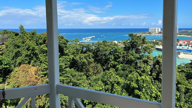 A gazebo with a view of a coastal landscape, including a pier and buildings in the distance.