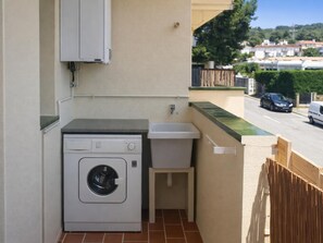 A laundry area with a washing machine and sink, a tiled floor, and a view of a street with parked cars. - Renovated apartment, near beach - 4 guests (Palamós)