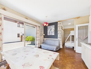 A room with a bed, a table with a patterned tablecloth, a painting on the wall, and a staircase leading to another level. - Charming studio at the slopes - 5 guests (Les Gets)